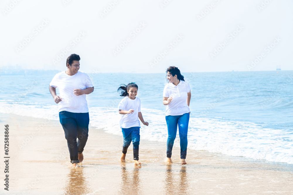 Happy indian Family of three enjoying summer vacation. Man and woman with their daughter running on beach. Happy indian Family of three enjoying summer vacation. Man and woman with their daughter running on beach.