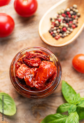 Jar with sun dried tomatoes with fresh herbs and spices.