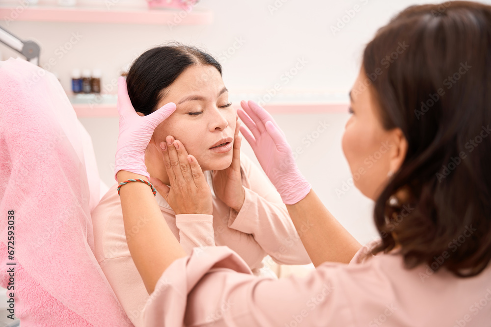 Cosmetologist analyzes the patients skin turgor