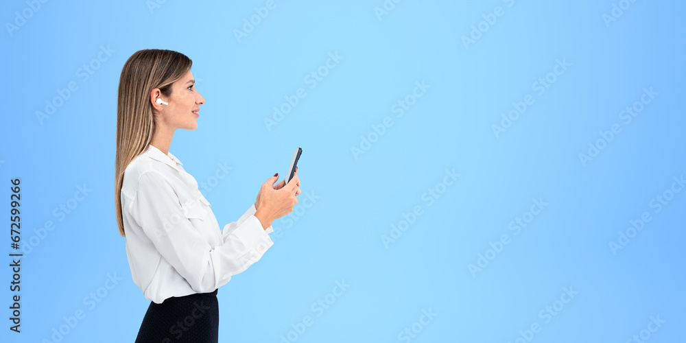 Smiling businesswoman typing in smartphone on empty copy space blue background Smiling businesswoman typing in smartphone on empty copy space blue background