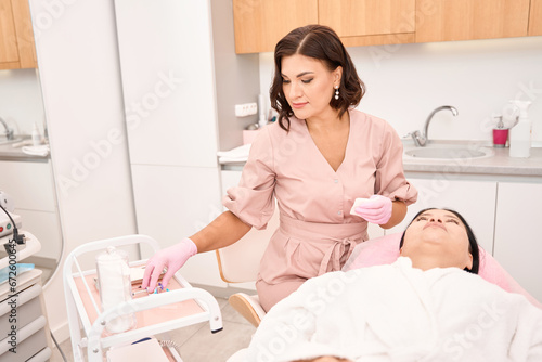 Esthetician takes a syringe from the injection table