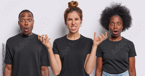 Collage of three mixed race young people stares bugged eyes and gesture with annoyance express disbelief and irritation dressed in casual black t shirts stand in row against white background photo