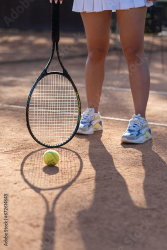 Close up woman playing tennis and ready to beat ball. Sports woman in mini skirt at tennis court. Professional tennis racquet with fitness girl legs wearing trainers © CinemaF