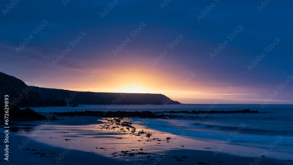 Beautiful sunrise landscape image of Kennack Sands in Cornwall UK wuth dramatic moody clouds and vibrant sunburst Beautiful sunrise landscape image of Kennack Sands in Cornwall UK wuth dramatic moody clouds and vibrant sunburst
