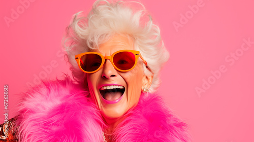 Fashionable elderly woman in sunglasses on a pink background.