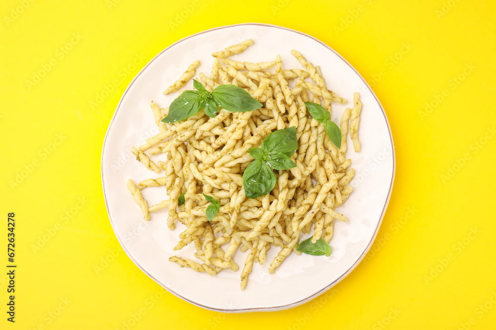 Plate of delicious trofie pasta with pesto sauce and basil leaves on yellow background, top view Plate of delicious trofie pasta with pesto sauce and basil leaves on yellow background, top view