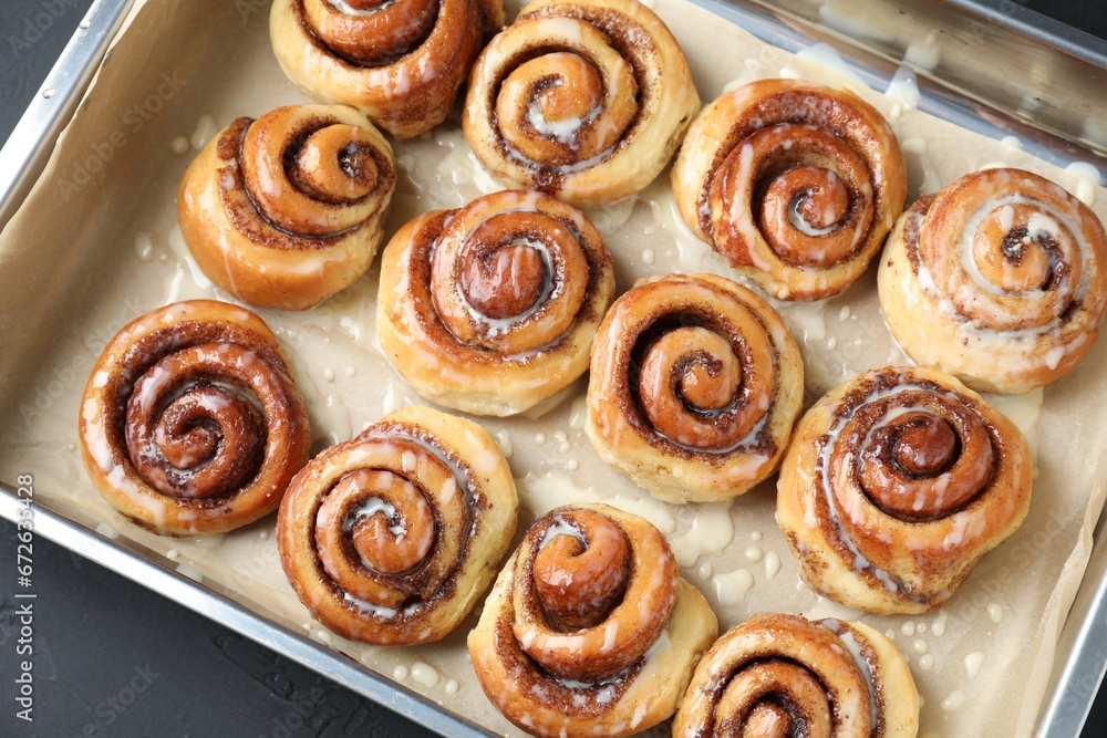 Fototapeta premium Baking dish with tasty cinnamon rolls on dark table, top view