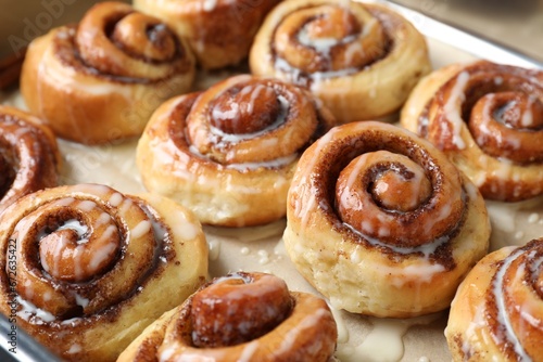 Tasty cinnamon rolls with cream on parchment paper  closeup