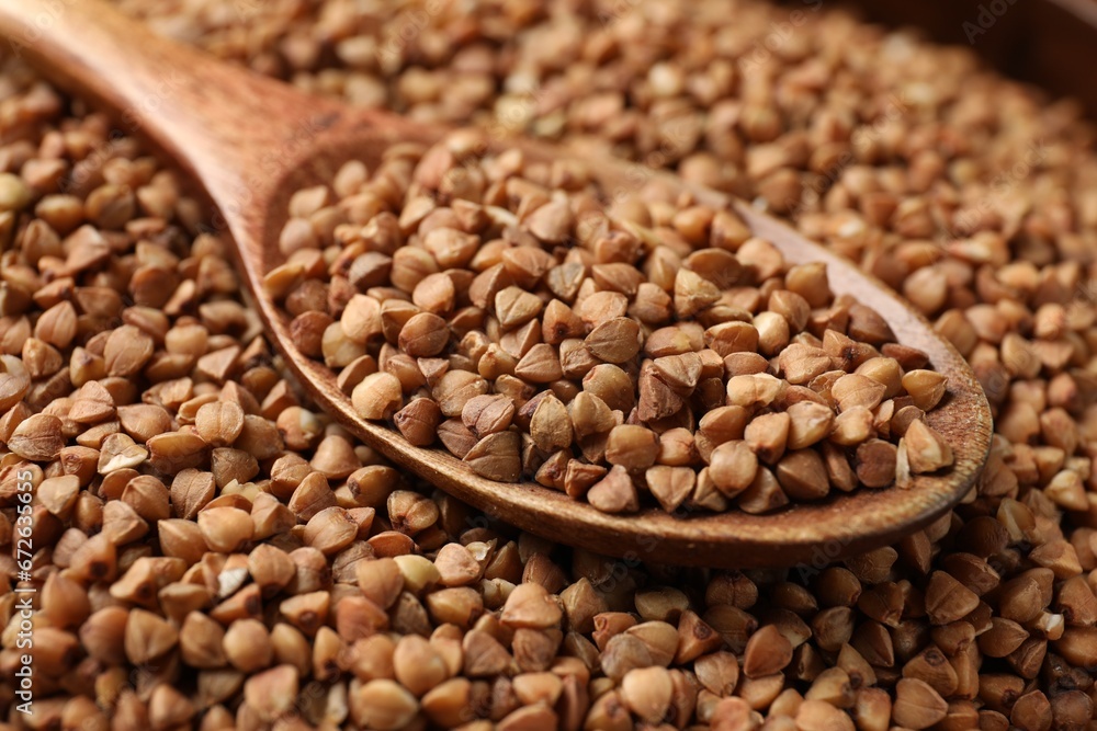 Wooden spoon on dry buckwheat grains, closeup Wooden spoon on dry buckwheat grains, closeup