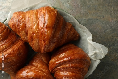 Delicious fresh croissants on grey textured table, top view