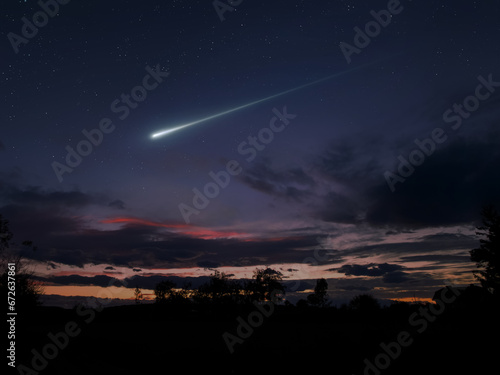 Night landscape with a meteor flash. A bright fireball in the sky above the clouds.