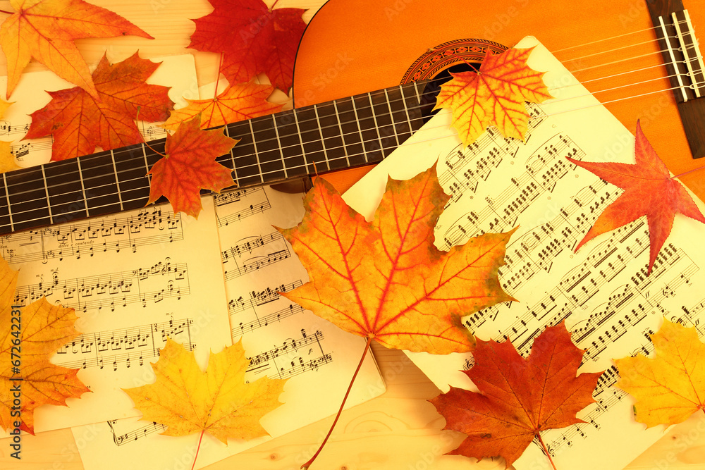 autumn melody, acoustic guitar, music paper and dry fallen maple leaves
