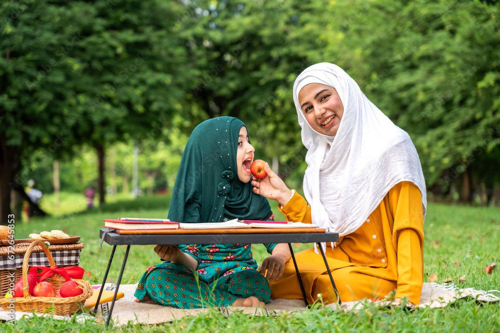 Portrait of happy religious enjoy happy love asian islam family muslim mother and little muslim girls child with hijab dress smiling and having fun moments good time, islam, ramadan in summer park Portrait of happy religious enjoy happy love asian islam family muslim mother and little muslim girls child with hijab dress smiling and having fun moments good time, islam, ramadan in summer park