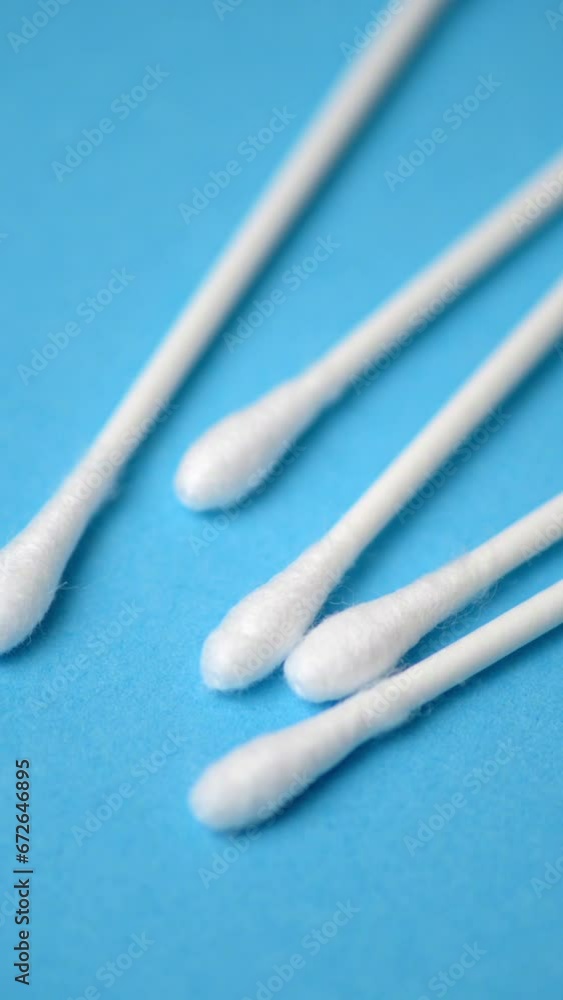 Close-up vertical video of white cotton swabs isolated on blue background Close-up vertical video of white cotton swabs isolated on blue background