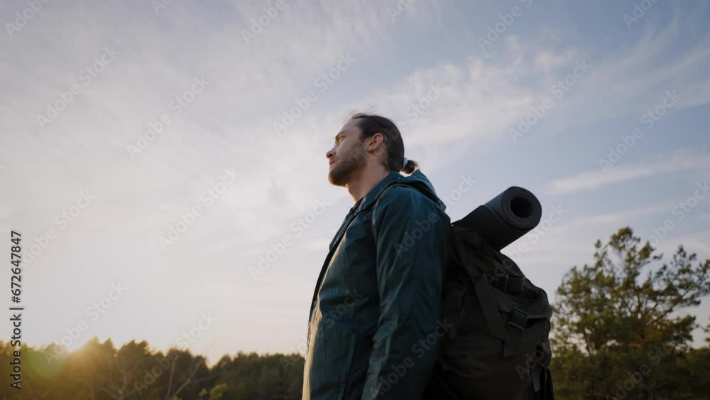 Hiking man standing near forest and looking at landscape Hiking man standing near forest and looking at landscape