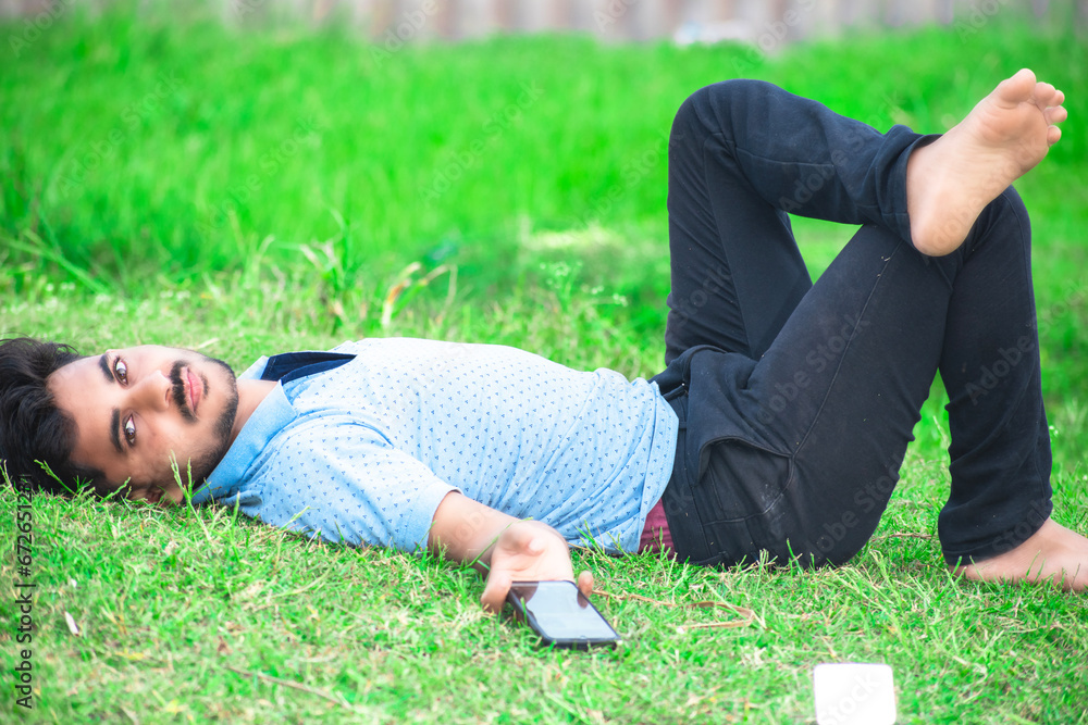 Beautiful young boy standing on grass background looking at camera, happy moment Beautiful young boy standing on grass background looking at camera, happy moment
