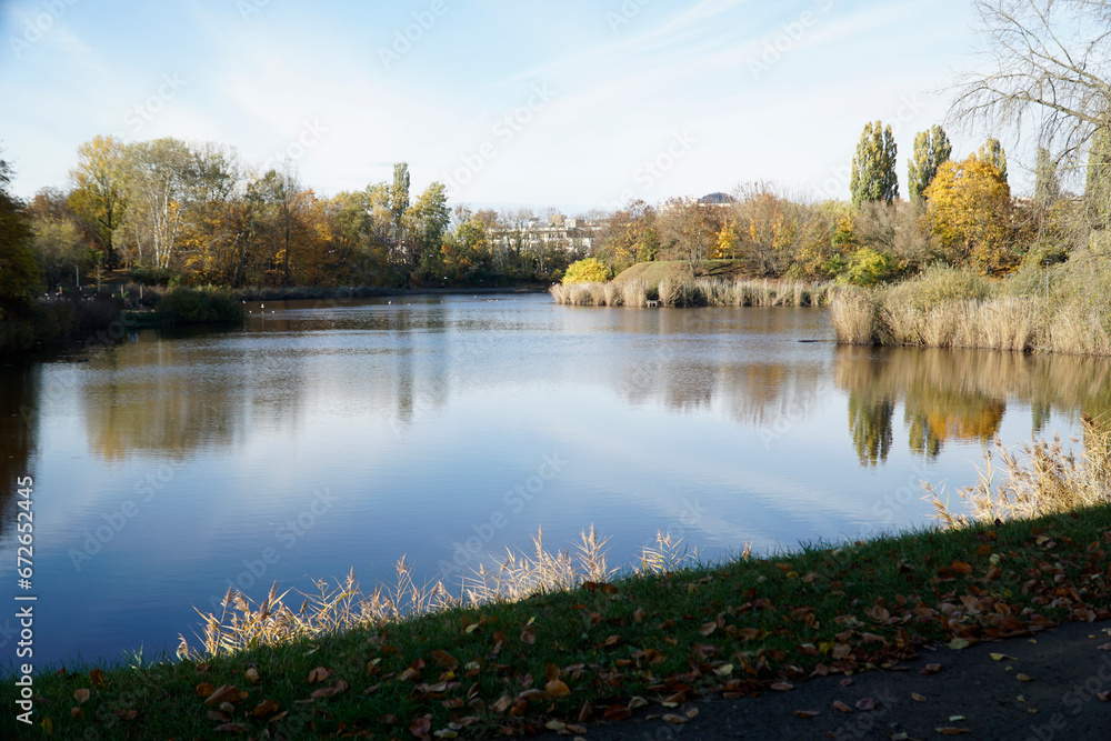 Lake in park in fall and trees reflecting in water Lake in park in fall and trees reflecting in water