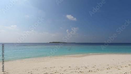 Maldives beach  waves wash the shore with white sand  clear azure water  and blue sky. Beauty  paradise  Indian ocean view