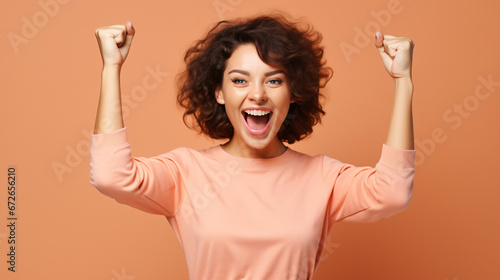 
Photo of cheerful overjoyed funny woman raise fists in victory see big bargains in phone isolated on beige color background photo