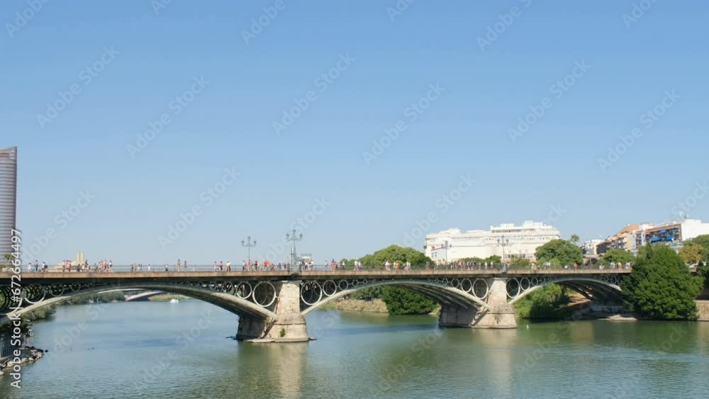 Panoramic view of famous Triana river bridge with perople and traffic in Seville city, European Spanish landmark Panoramic view of famous Triana river bridge with perople and traffic in Seville city, European Spanish landmark