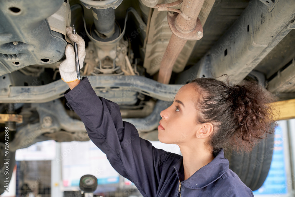 Technician woman is checking under a car for maintainance vehicle in garage. Technician woman is checking under a car for maintainance vehicle in garage.