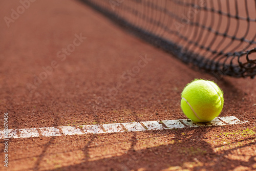 Tennis, ball and clay court, net and line for exercise, training and fitness outdoor in summer. Sports, netting and closeup of sphere on ground for game, competition and workout on field and pitch © Nicola Katie/peopleimages.com