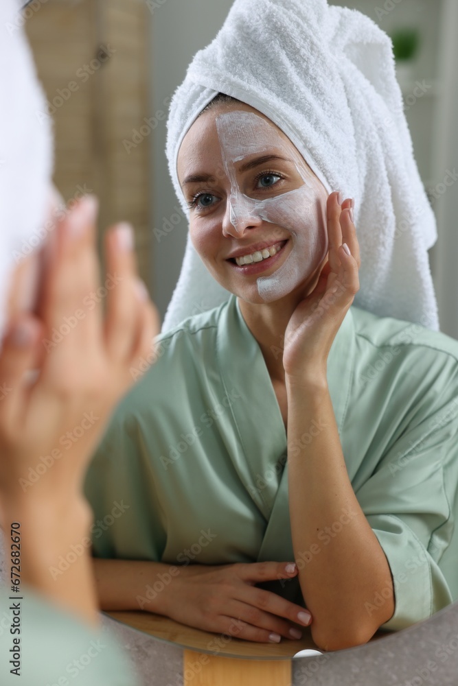 Woman with face mask near mirror in bathroom. Spa treatments Woman with face mask near mirror in bathroom. Spa treatments