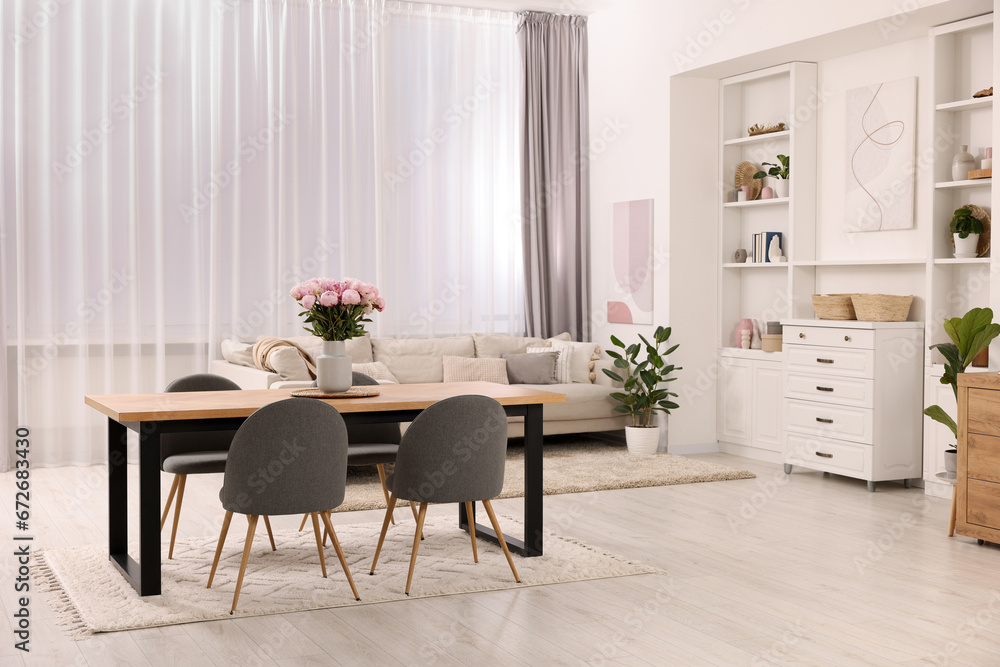 Table, chairs, sofa and vase with peonies in stylish dining room Table, chairs, sofa and vase with peonies in stylish dining room