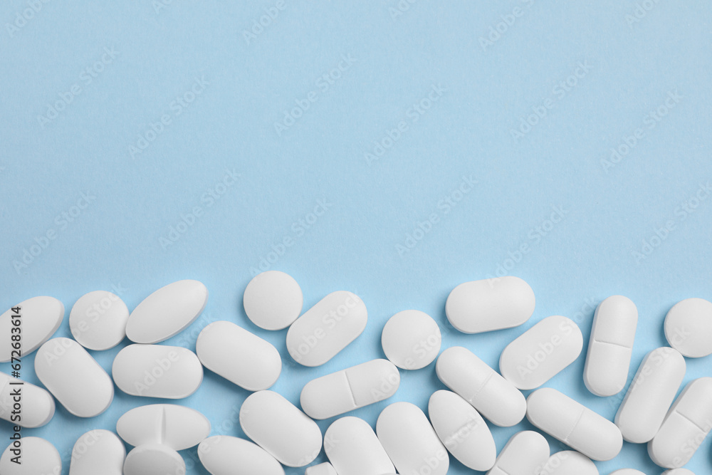 Many pills on light blue background, flat lay. Space for text - obrazy, fototapety, plakaty 