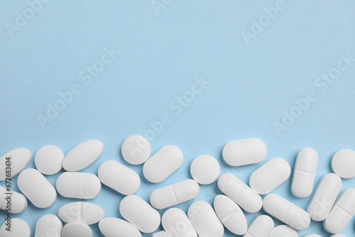 Many pills on light blue background, flat lay. Space for text