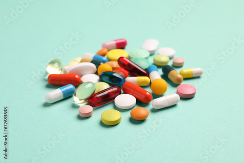 Pile of many different pills on turquoise background.