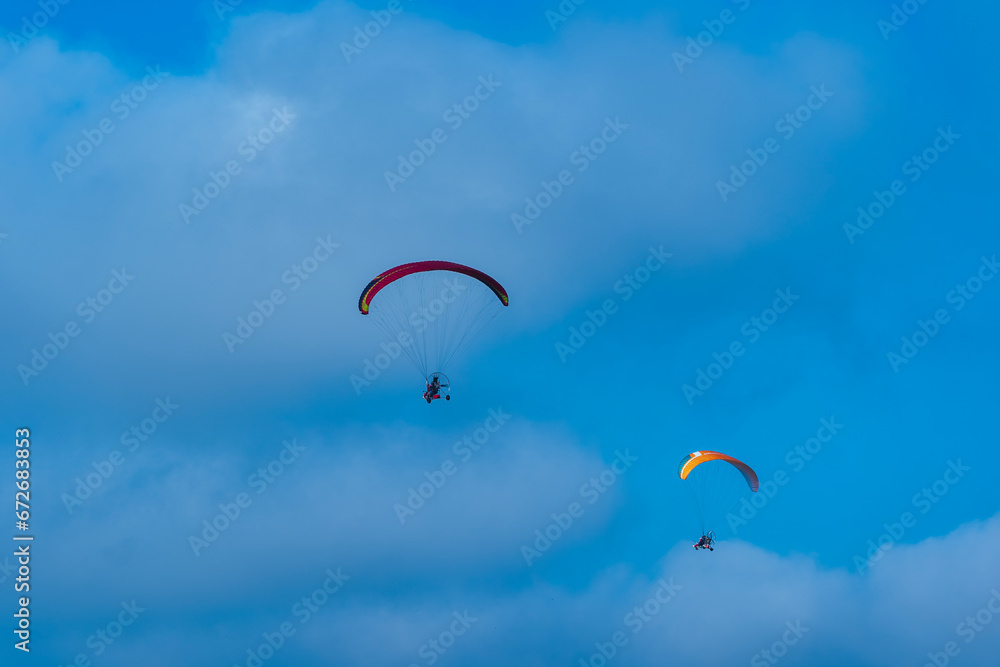 Flying with paramotor in the blue sky - Man riding paramotor in the blue sky background Flying with paramotor in the blue sky - Man riding paramotor in the blue sky background
