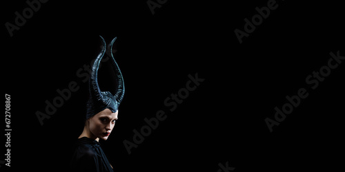 beautiful woman with devil witch horns in sorceress costume. Woman in Halloween costume posing against black background. photo