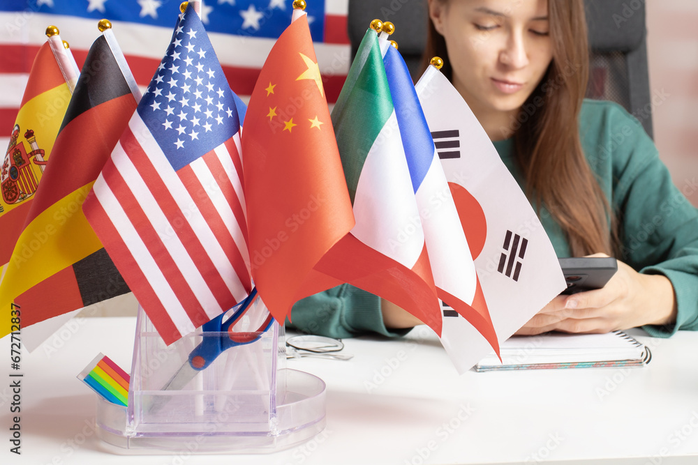 Student learns languages on the phone using a mobile application, online language course, flag backgrounds, eLearning - obrazy, fototapety, plakaty 