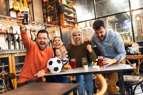 Excited soccer fans celebrating while watching soccer match on TV in bar. © Mediteraneo