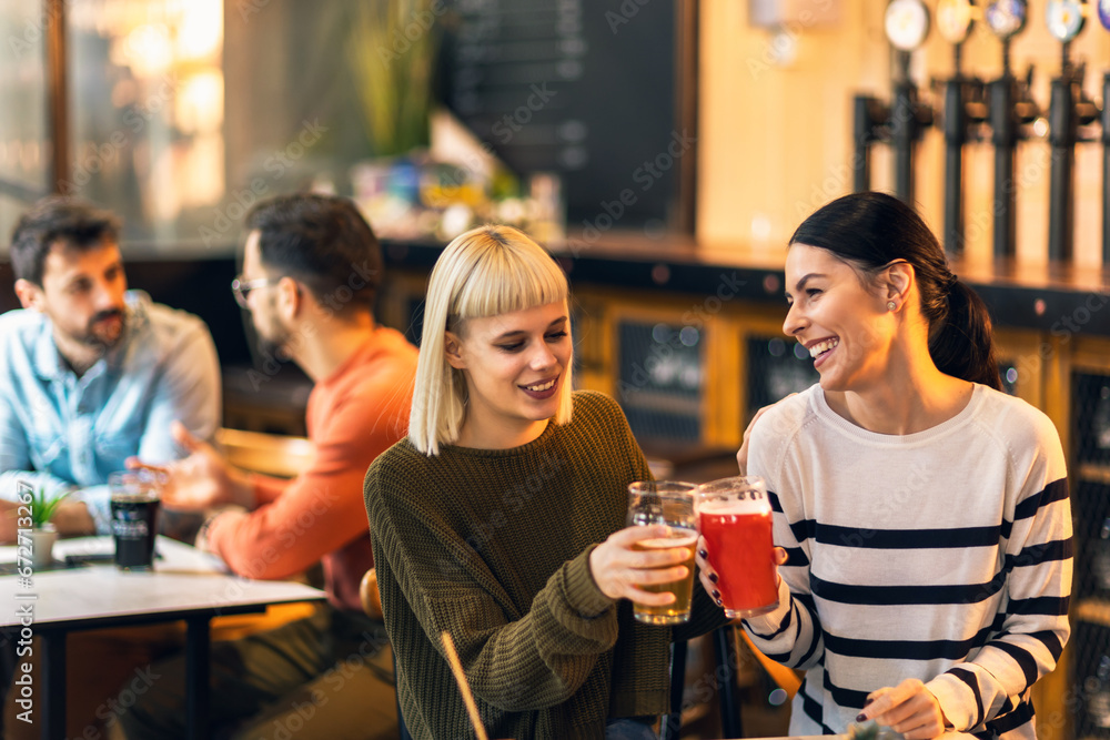 Smiling young friends drinking craft beer in pub Smiling young friends drinking craft beer in pub