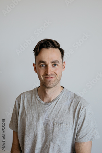 Young man dorky smile grey shirt plain background photo