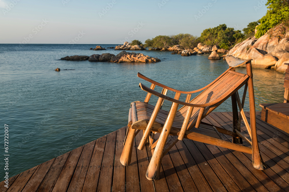 Wood sunbed deck at resort patio by sea in morning, Ko Man Klang