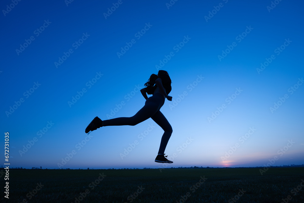 silhouette of a young woman running against a background of blue sky during sunset silhouette of a young woman running against a background of blue sky during sunset