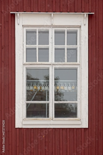 White frame window on the wall of a red painted building.