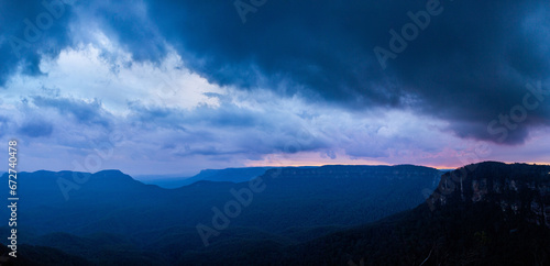 Dramatic stormy sky over layered blue mountains at nightfall
