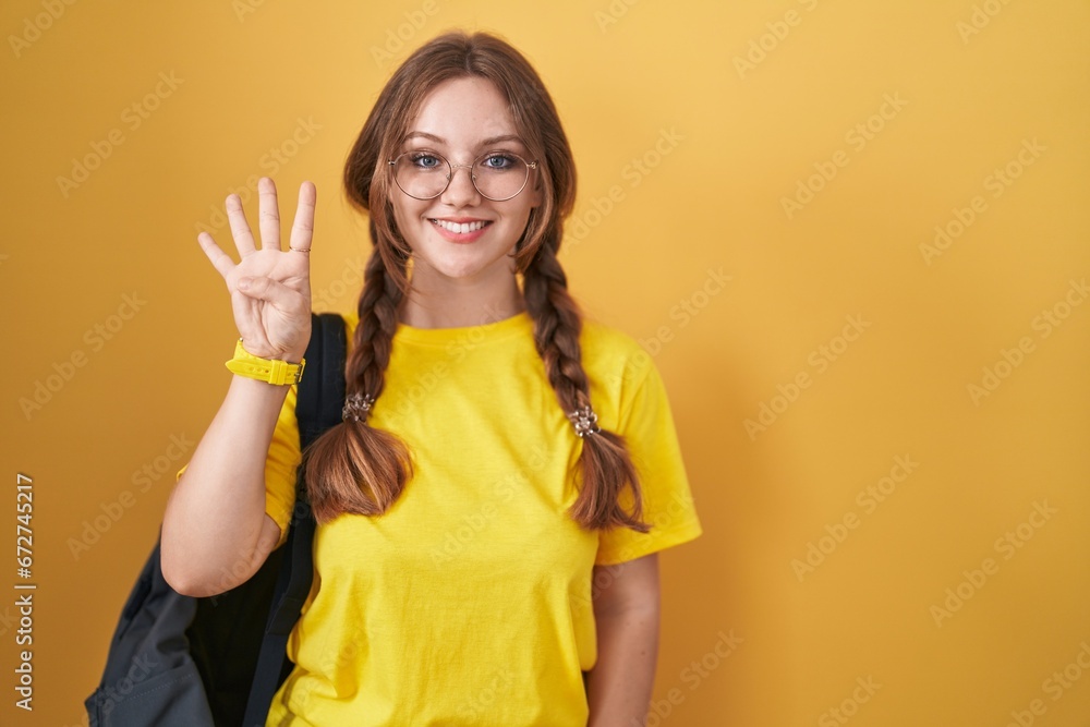 Young caucasian woman wearing student backpack over yellow background showing and pointing up with fingers number four while smiling confident and happy. Young caucasian woman wearing student backpack over yellow background showing and pointing up with fingers number four while smiling confident and happy.