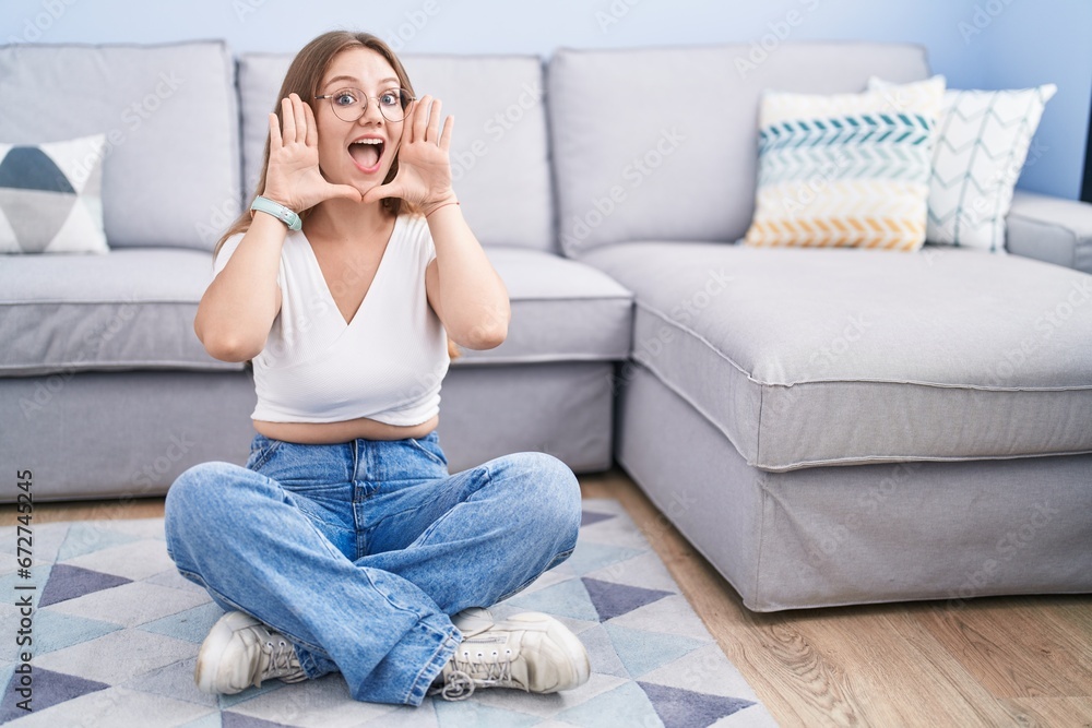 Young caucasian woman sitting on the floor at the living room smiling cheerful playing peek a boo with hands showing face. surprised and exited Young caucasian woman sitting on the floor at the living room smiling cheerful playing peek a boo with hands showing face. surprised and exited