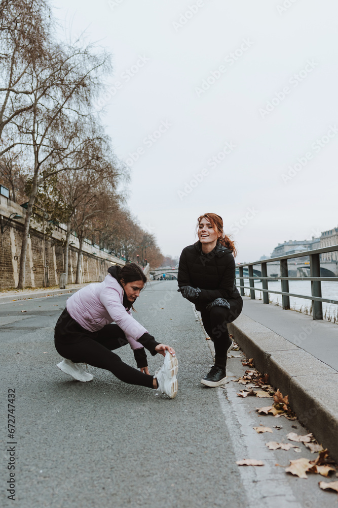 Two girls or hispanic couple of women in sports outfit stretching and doing exercises outdoors in winter weather Two girls or hispanic couple of women in sports outfit stretching and doing exercises outdoors in winter weather