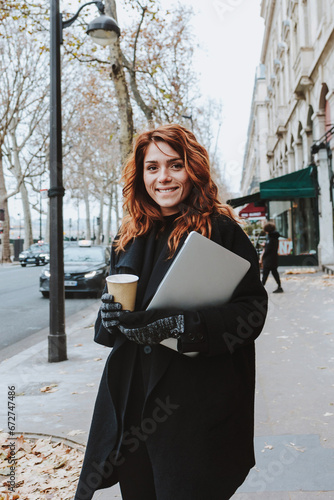 hispanic redhead business woman with a cup of coffee walking in an urban city in Europe