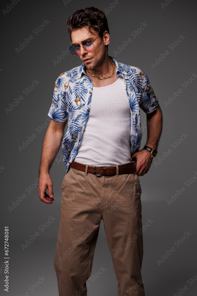 Well dressed man in aloha shirt, sunglasses and tank top posing isolated on grey Well dressed man in aloha shirt, sunglasses and tank top posing isolated on grey