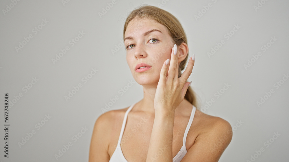 Young blonde woman touching face over isolated white background Young blonde woman touching face over isolated white background
