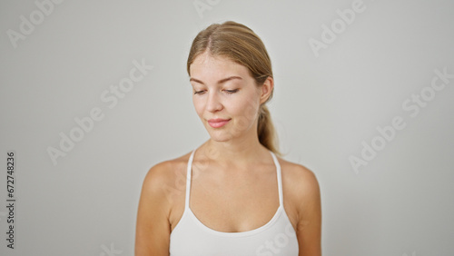 Young blonde woman standing with serious face over isolated white background