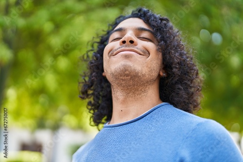Young latin man breathing with closed eyes at park