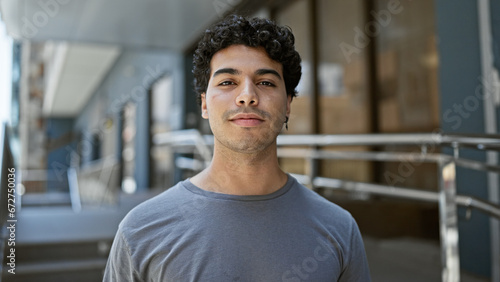 Young latin man standing with serious expression at street